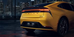 A yellow Toyota Prius with a nighttime city background.